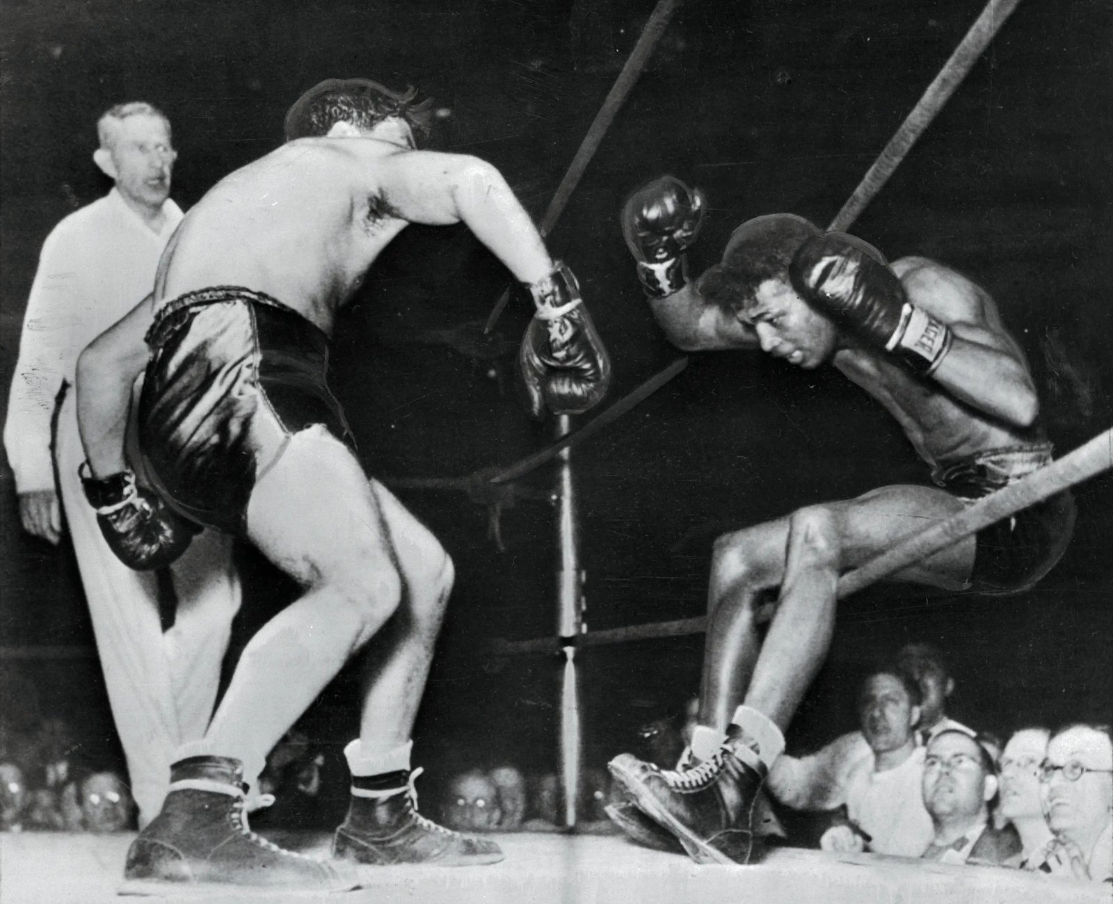 (Original Caption) Victorious in 129 successive fights, including 40 as a pro, Ray Robinson falls through the ropes of a Detroit ring, under the impact of Jake LaMotta's fists. Robinson got back in the ring, but lost the decision in ten rounds.