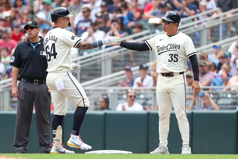Minnesota Twins' Jose Miranda, left, celebrates his RBI single with first base coach Hank Conger during a 2024 game.
