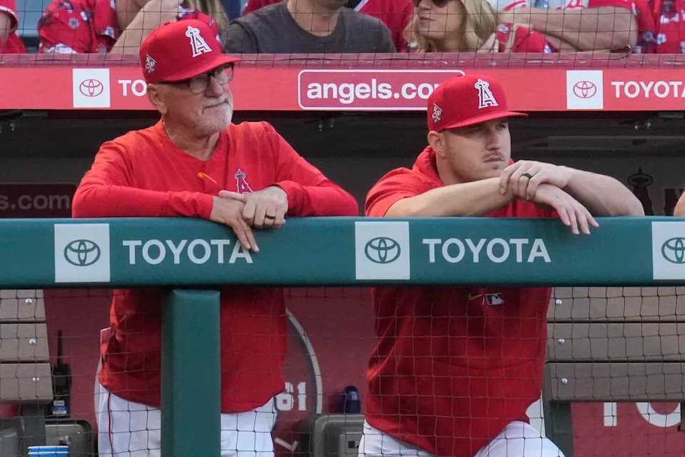 Angels manager Joe Maddon, left, and Mike Trout stand in the dugout during a game against the Orioles in July 2021.