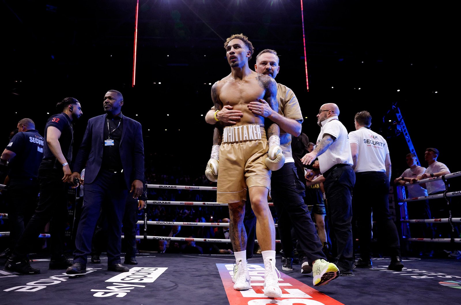 Whittaker is restrained by coach Andy Lee after stopping Liam Cameron in their rematch