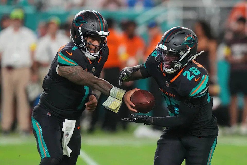 Miami Dolphins running back De'Von Achane takes a hand off from quarterback Tua Tagovailoa.