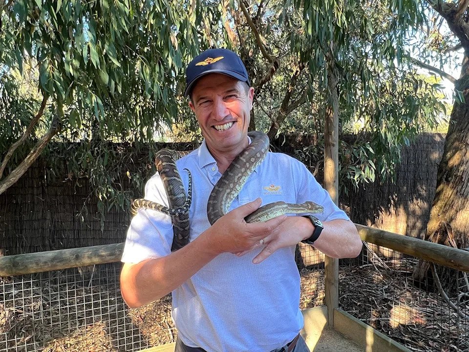 Golf photographer Gary Lisbon tries to get comfortable with a python at Moonlit Sanctuary in Victoria, Australia (Jason Lusk/Golfweek)