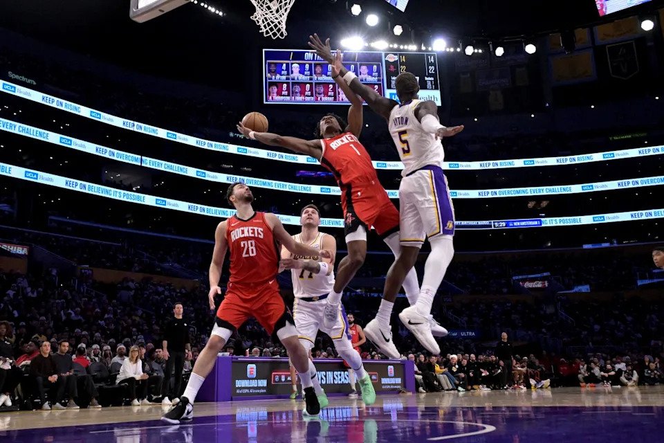 Rockets guard Amen Thompson drives to the basket and shoots under pressure from Lakers center Deandre Ayton.