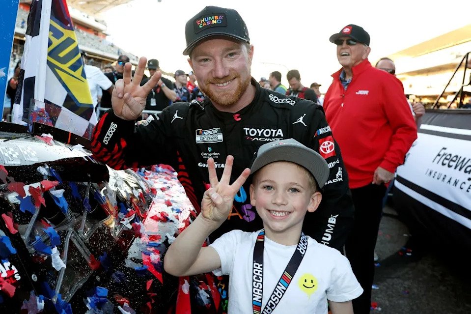 Tyler Reddick, driver of the #45 Chumba Casino Toyota, and son, Beau Reddick pose with the winner sticker on his car in victory lane after winning his third race in a row to start the 2026 NASCAR season winning the NASCAR Cup Series DuraMax Grand Prix. Getty Images