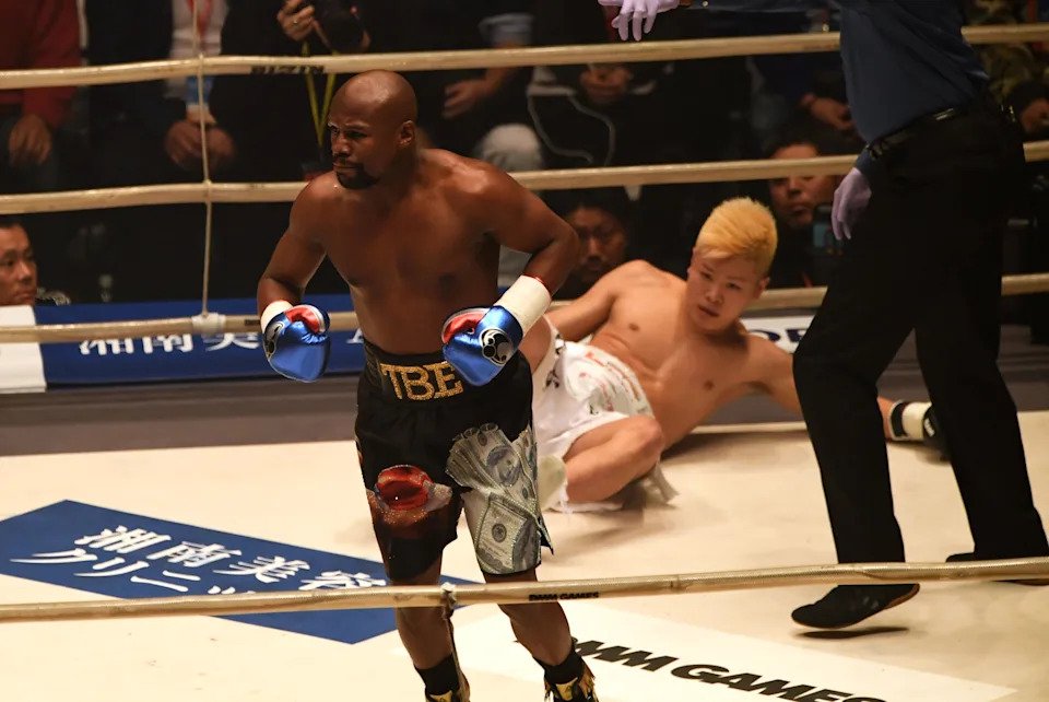 TOPSHOT - US boxing legend Floyd Mayweather Jr (L) knocks down Kickboxer Tenshin Nasukawa of Japan (C) during their exhibition match at Saitama Super Arena in Saitama on December 31, 2018. - Floyd Mayweather beat Japanese kickboxing phenomenon Tenshin Nasukawa by a technical knock-out in the first round of a New Year's Eve "exhibition" bout that brought the US boxing superstar out of retirement. (Photo by Toshifumi KITAMURA / AFP)        (Photo credit should read TOSHIFUMI KITAMURA/AFP via Getty Images)