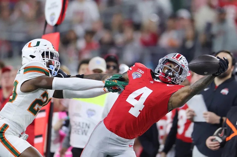 Jeremiah Smith of the Ohio State Buckeyes attempts a catch in front of OJ Frederique Jr. of the <a class="link " href="https://sports.yahoo.com/ncaaf/teams/miami-(fl)/" data-i13n="sec:content-canvas;subsec:anchor_text;elm:context_link" data-ylk="slk:Miami Hurricanes;sec:content-canvas;subsec:anchor_text;elm:context_link;itc:0" data-yga="{"yLinkElement":"context_link","yModuleName":"content-canvas","yLinkText":"Miami Hurricanes","ySubModuleName":"anchor_text","yHasCommerce":false}">Miami Hurricanes</a>. Getty Images