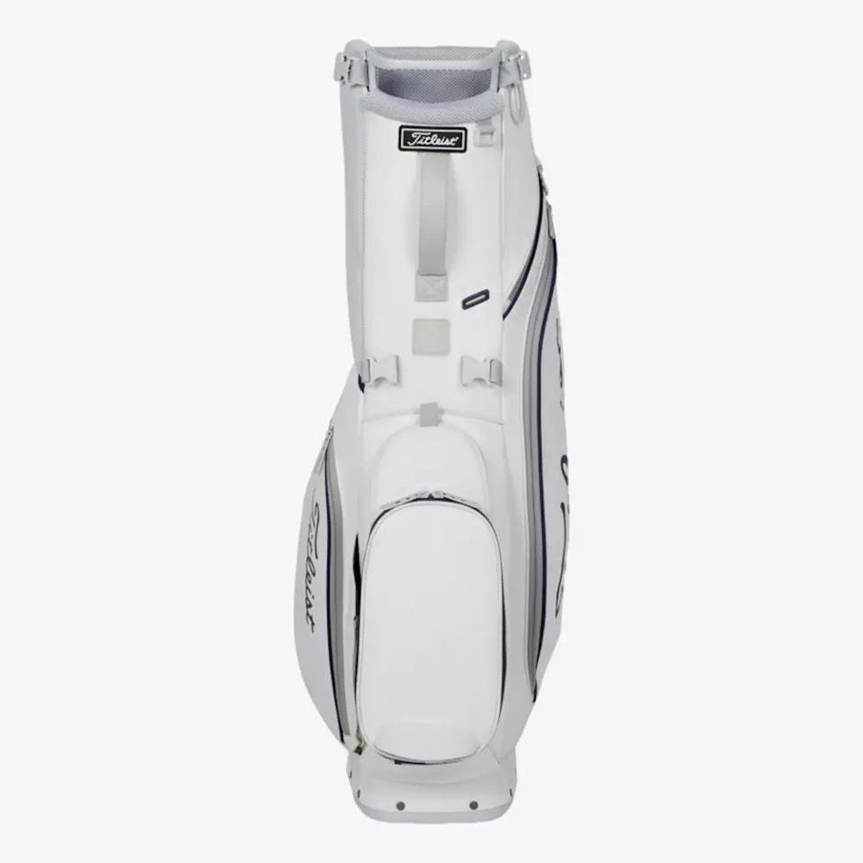 A white Titleist golf bag with multiple zippered compartments and handles, standing upright on a plain light background. The Titleist logo is visible on the side and near the top—an excellent choice among the best golf bags 2026.