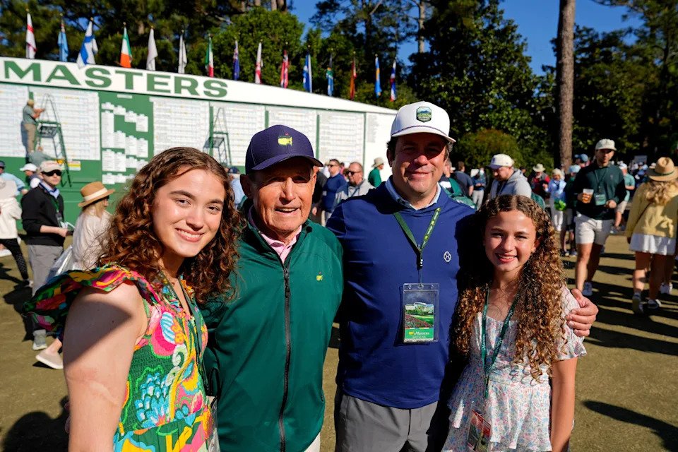 Lou Miller (blue cap) poses for a photo with his granddaughters Porter (left), 17, and Neely (right), 12, and his son Brent Miller (white cap), all of Chapin, South Carolina, in front of the Masters scoreboard during the second round of the Masters Tournament at Augusta National Golf Club on April 10, 2026. Mandatory Credit: Katie Goodale-Imagn Images