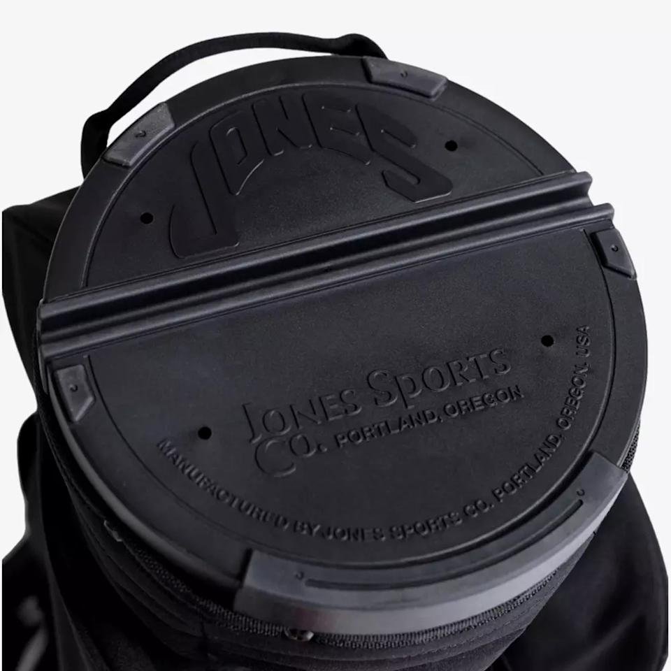 Close-up of a black circular cover with embossed text JONES and Jones Sports Co. Portland, Oregon on a bag, exemplifying the sturdy construction found in the best golf bags 2026, with a convenient top handle.