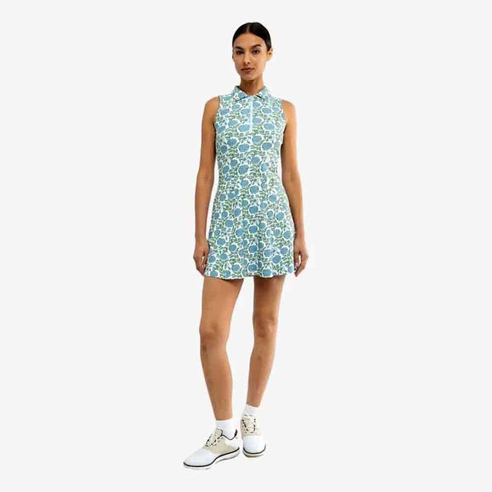 A woman stands against a plain background wearing a sleeveless, blue and green floral-patterned dress and white athletic shoes with ankle socks—an effortless, fresh look perfect for celebrating Mother’s Day.