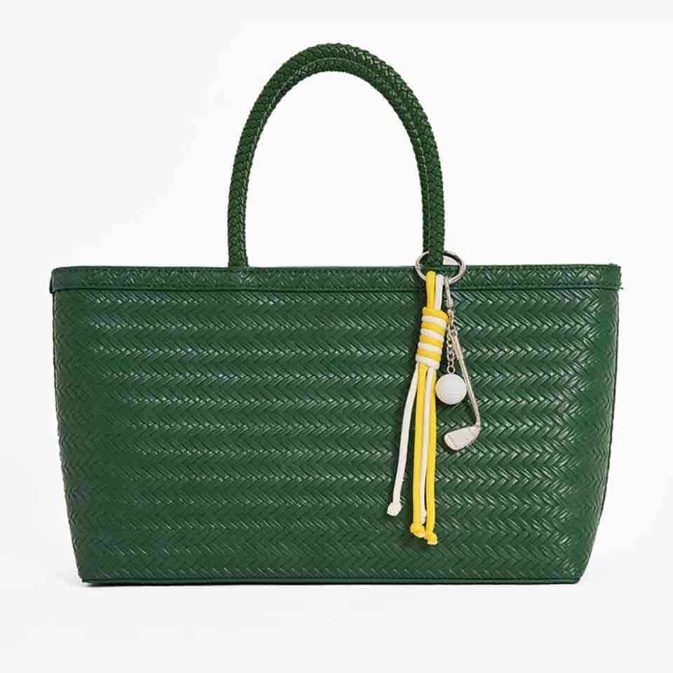 A green woven tote bag with a single handle, featuring a decorative keychain with yellow and white tassels and a white ball charm—perfect for stylish accessories or thoughtful Mother’s Day gifts.